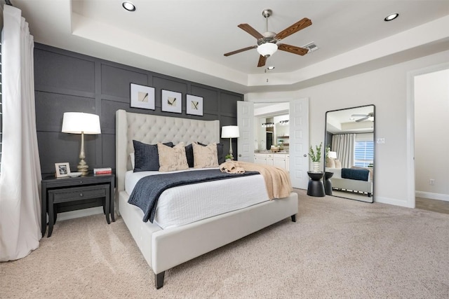 bedroom featuring visible vents, a tray ceiling, light carpet, recessed lighting, and a decorative wall