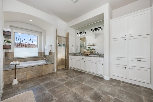 bathroom featuring a bath, a shower stall, double vanity, and a sink