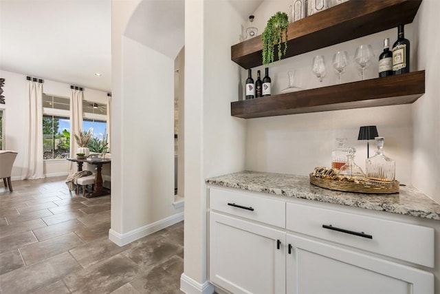 indoor dry bar with baseboards, arched walkways, and recessed lighting