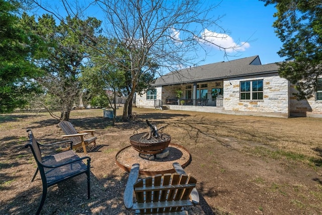 rear view of house with stone siding and an outdoor fire pit