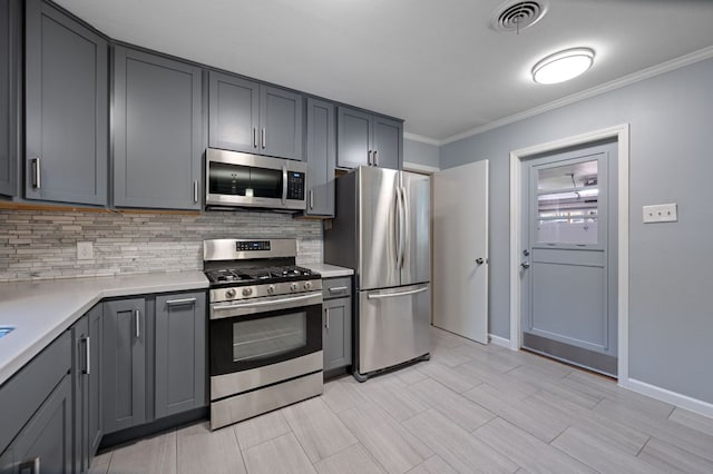 2709 Cascade Dr, Austin, TX 78757 - kitchen featuring stainless steel appliances, backsplash, gray cabinets, light countertops, and ornamental molding