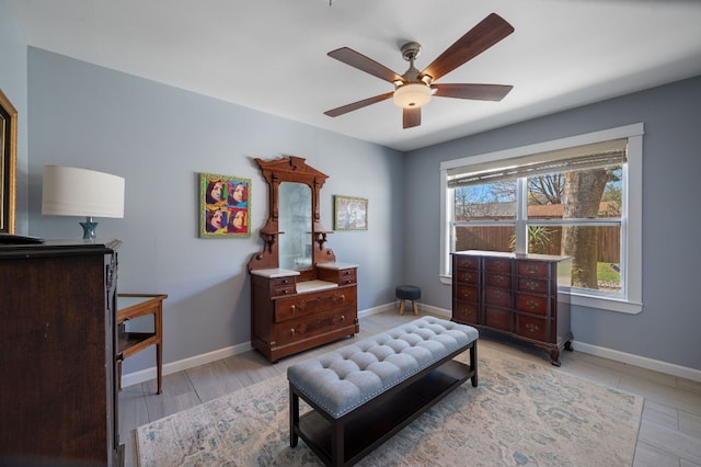 living area featuring baseboards and ceiling fan