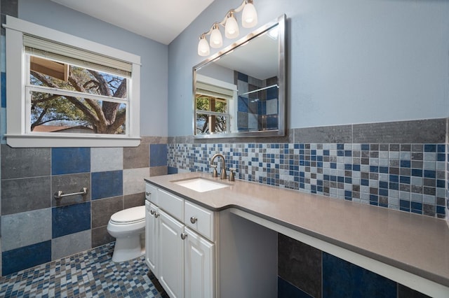 bathroom featuring vanity, a shower, wainscoting, tile walls, and toilet