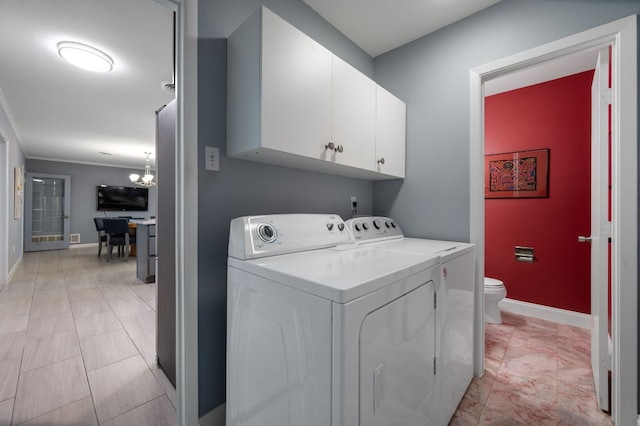 washroom featuring baseboards, cabinet space, a chandelier, and washing machine and clothes dryer