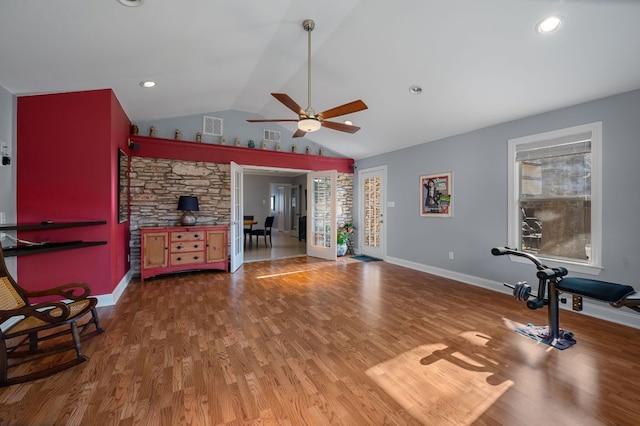 exercise room with visible vents, a ceiling fan, wood finished floors, baseboards, and lofted ceiling