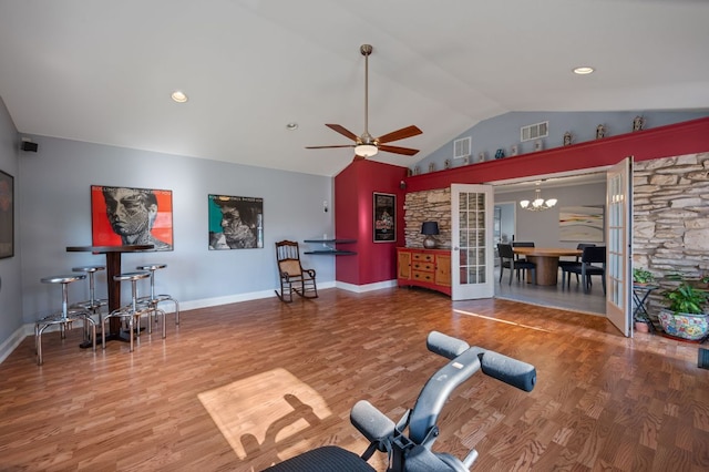 workout area featuring ceiling fan with notable chandelier, lofted ceiling, wood finished floors, and visible vents