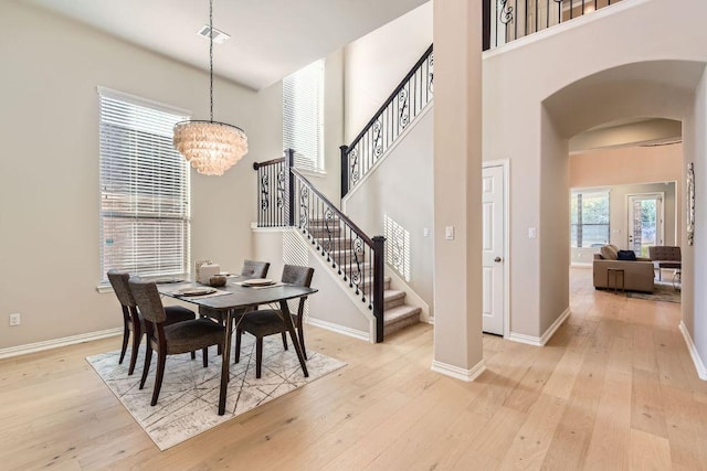 dining room featuring arched walkways, a notable chandelier, and light wood-style floors