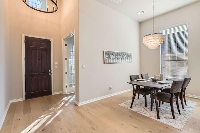 dining area with visible vents, light wood-style floors, and an inviting chandelier