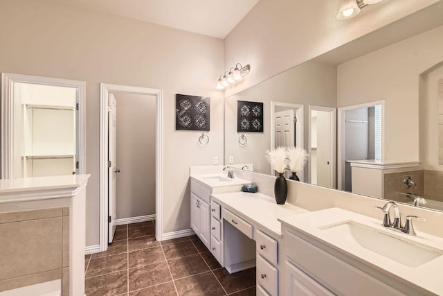 full bathroom featuring tile patterned flooring, double vanity, baseboards, and a sink