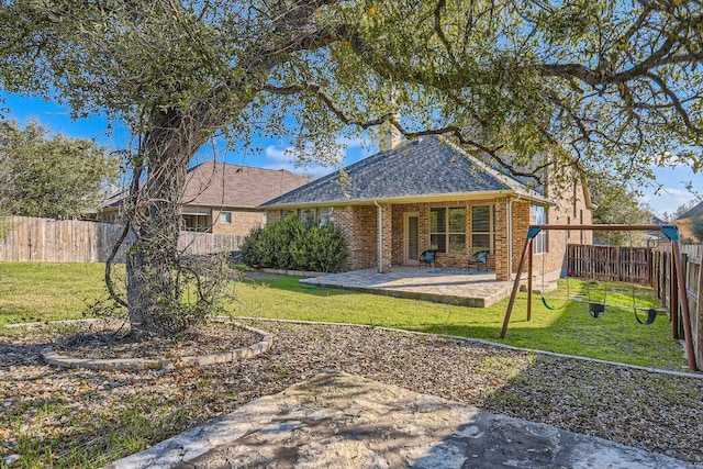 back of property featuring brick siding, a fenced backyard, a lawn, and a patio area