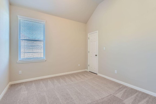 empty room with baseboards, light colored carpet, and vaulted ceiling