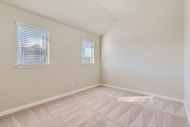 unfurnished room with baseboards, lofted ceiling, and light carpet