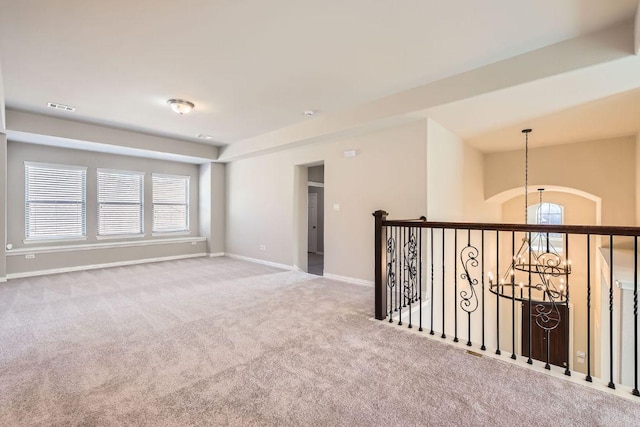 empty room featuring carpet flooring, a notable chandelier, baseboards, and visible vents