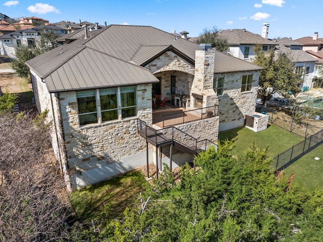 rear view of house featuring stone siding, metal roof, and a yard