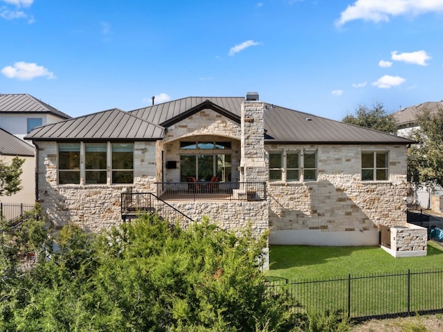 back of property with metal roof, stone siding, a yard, and a standing seam roof