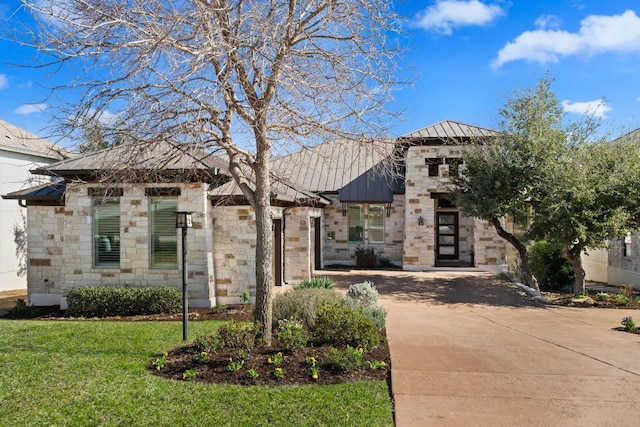 view of front facade featuring metal roof, stone siding, a front lawn, and a standing seam roof