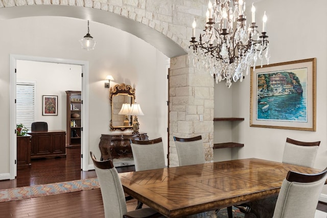 dining area with arched walkways, a notable chandelier, baseboards, and hardwood / wood-style flooring