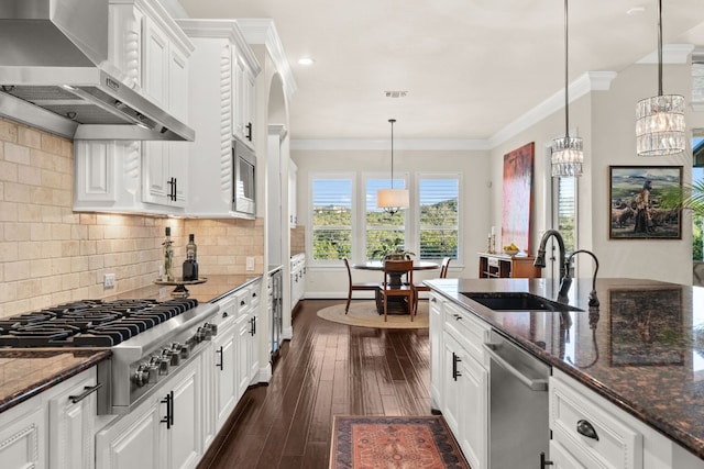 kitchen with visible vents, wall chimney range hood, ornamental molding, stainless steel appliances, and a sink