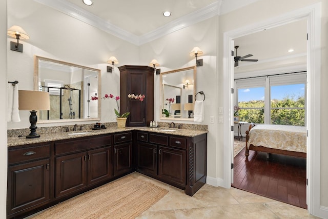 ensuite bathroom featuring a ceiling fan, double vanity, a stall shower, a sink, and crown molding