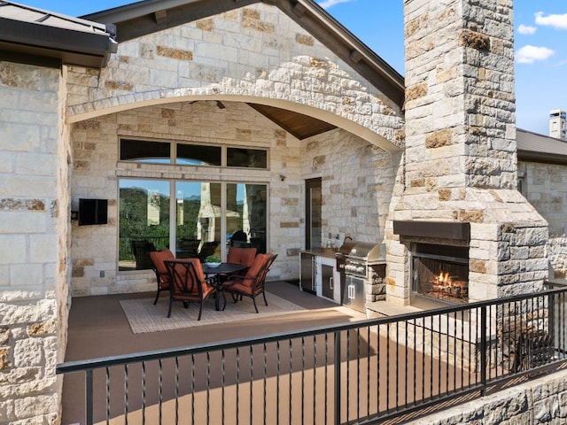 view of patio with grilling area, area for grilling, outdoor dining space, and an outdoor stone fireplace