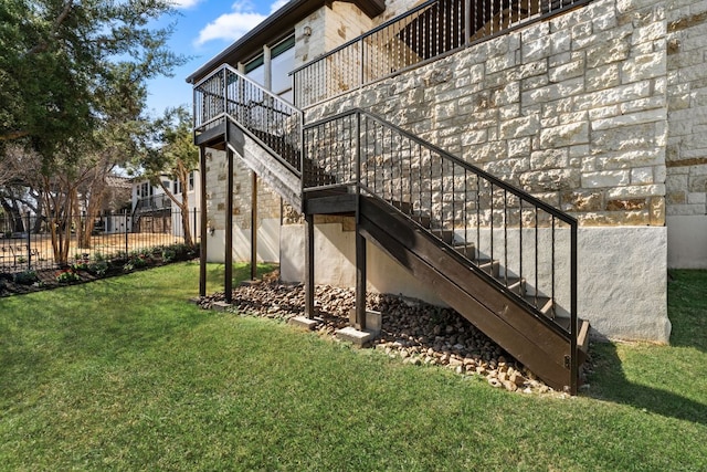 view of home's exterior featuring stairway, a lawn, and fence