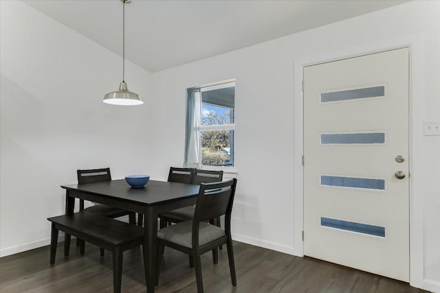 dining room featuring dark wood-type flooring, baseboards, and vaulted ceiling