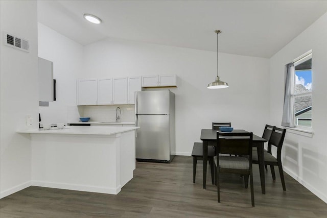 kitchen with visible vents, dark wood-type flooring, light countertops, a peninsula, and freestanding refrigerator