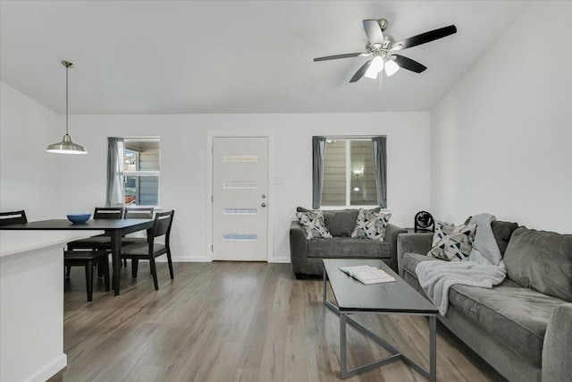 living area with vaulted ceiling, baseboards, ceiling fan, and wood finished floors