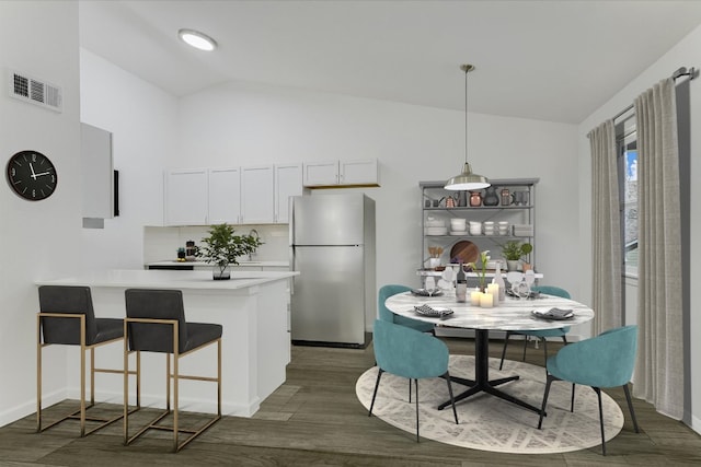 710 W 34th St Unit 205, Austin, TX 78705 - kitchen with freestanding refrigerator, dark wood finished floors, a peninsula, light countertops, and a breakfast bar area