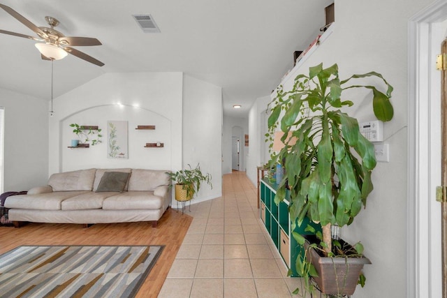 living area with light tile patterned floors, visible vents, lofted ceiling, and ceiling fan