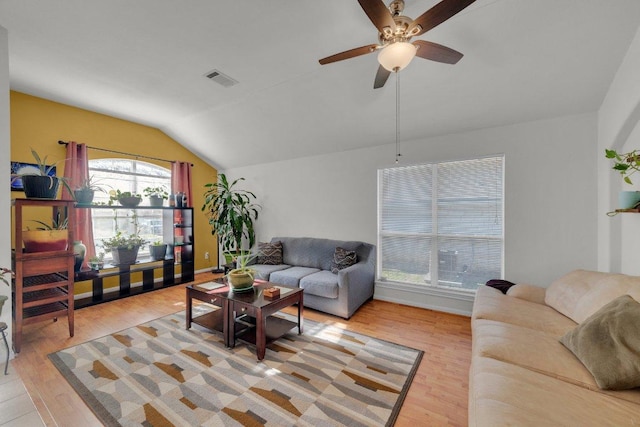 living area with lofted ceiling, a ceiling fan, visible vents, and light wood finished floors