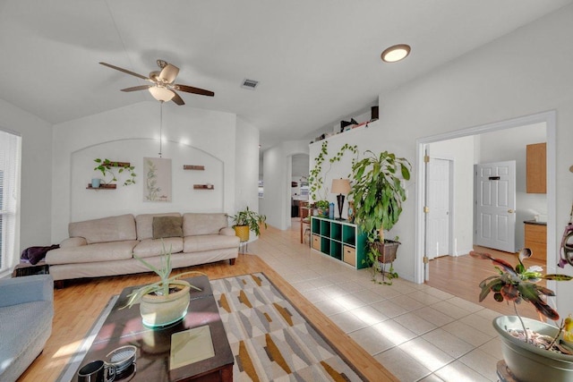 tiled living area with arched walkways, visible vents, a ceiling fan, and vaulted ceiling