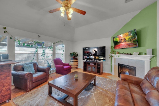 living area featuring lofted ceiling, a ceiling fan, wood finished floors, and a tiled fireplace