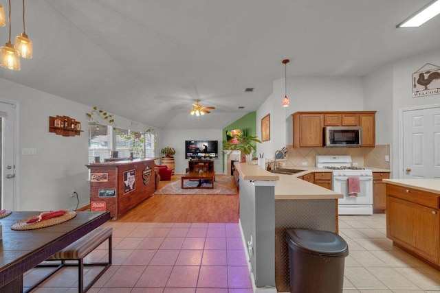 kitchen featuring stainless steel microwave, white range with gas stovetop, light tile patterned flooring, and a sink