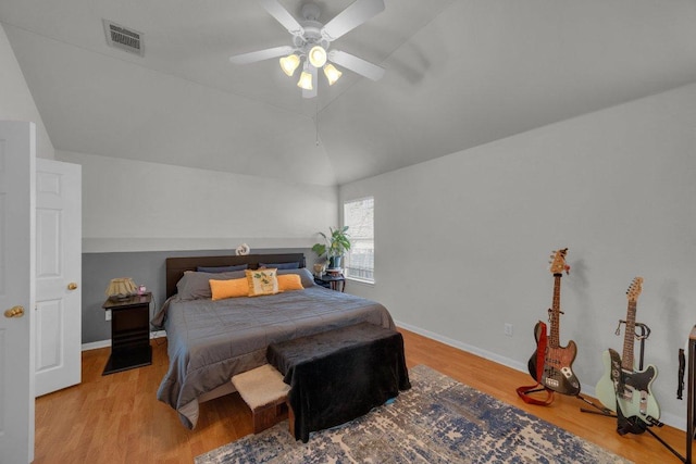 bedroom featuring vaulted ceiling, visible vents, baseboards, and wood finished floors