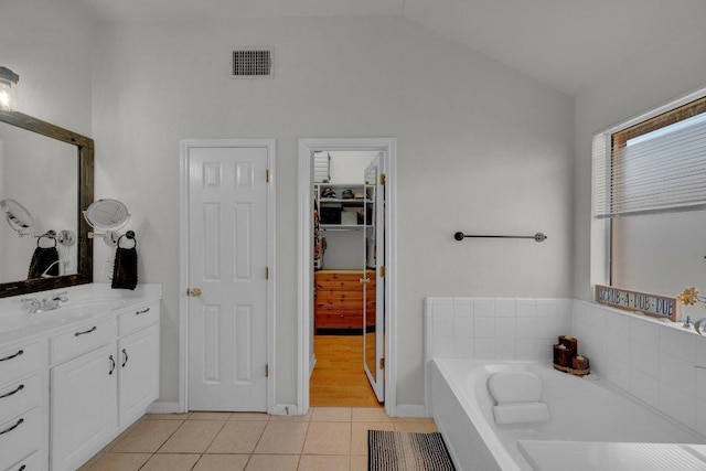 full bathroom featuring visible vents, tile patterned flooring, lofted ceiling, a bath, and vanity