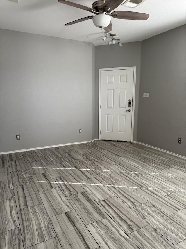 spare room featuring a ceiling fan and baseboards