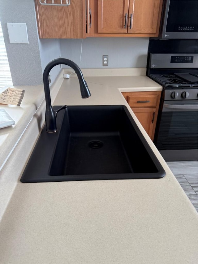 room details with brown cabinetry, appliances with stainless steel finishes, light countertops, and a sink