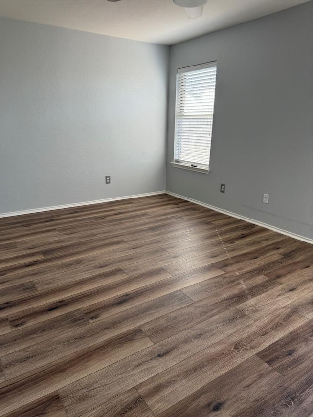 empty room with baseboards and dark wood finished floors