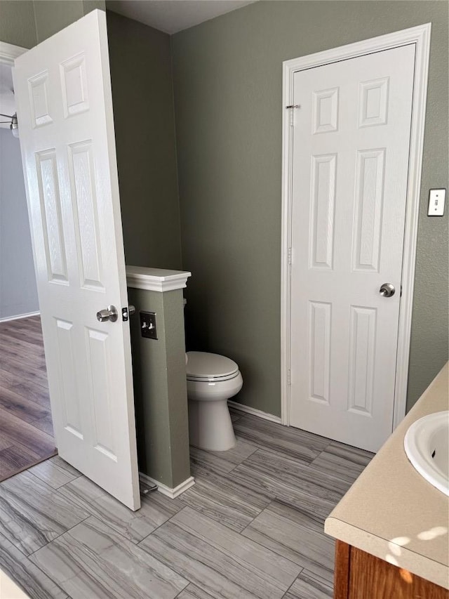 bathroom with toilet, vanity, and baseboards