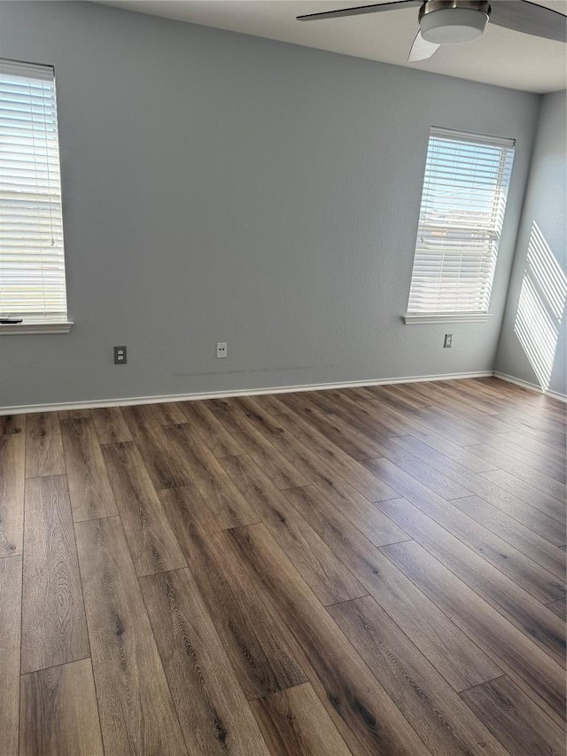 unfurnished room with dark wood-style floors, baseboards, and ceiling fan