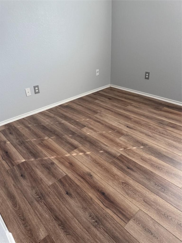 empty room with dark wood-type flooring and baseboards