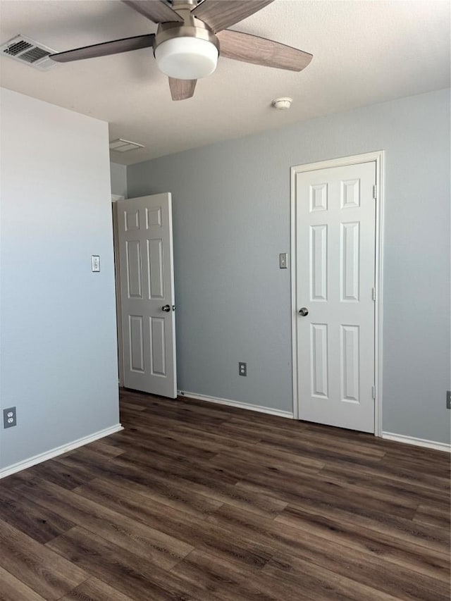 unfurnished room with dark wood-type flooring, baseboards, visible vents, and ceiling fan