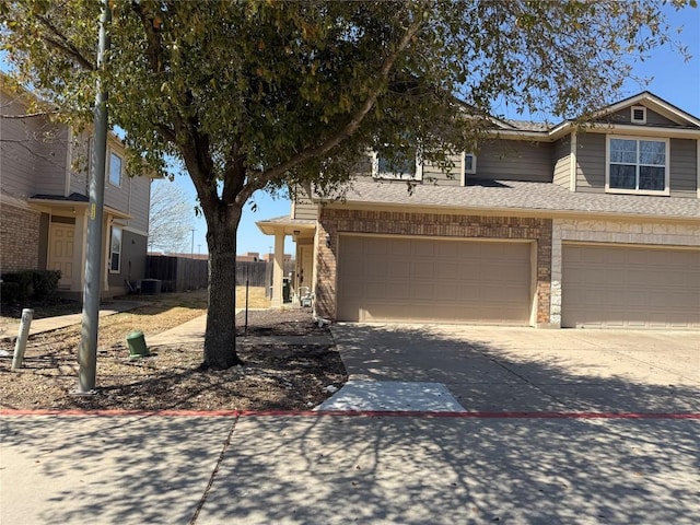 view of front of property with concrete driveway, an attached garage, and fence