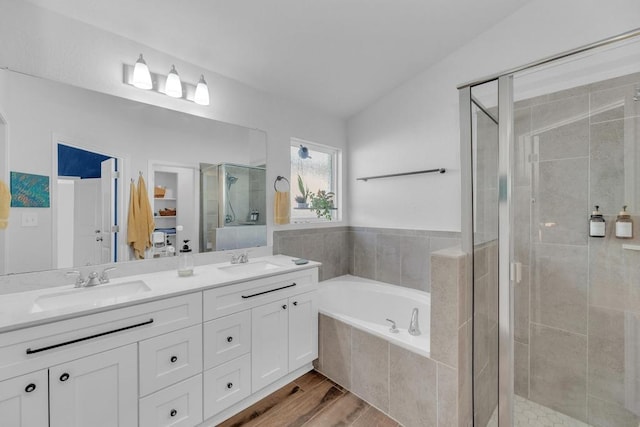 full bathroom with a bath, a stall shower, double vanity, and a sink