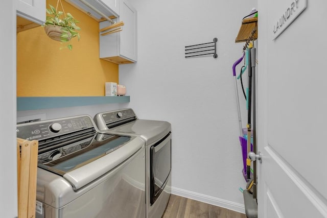 clothes washing area with washer and dryer, baseboards, cabinet space, and wood finished floors