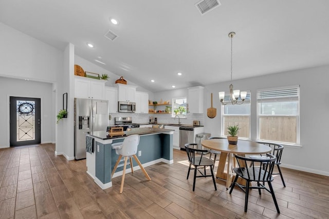 dining area with visible vents, wood finished floors, recessed lighting, an inviting chandelier, and lofted ceiling