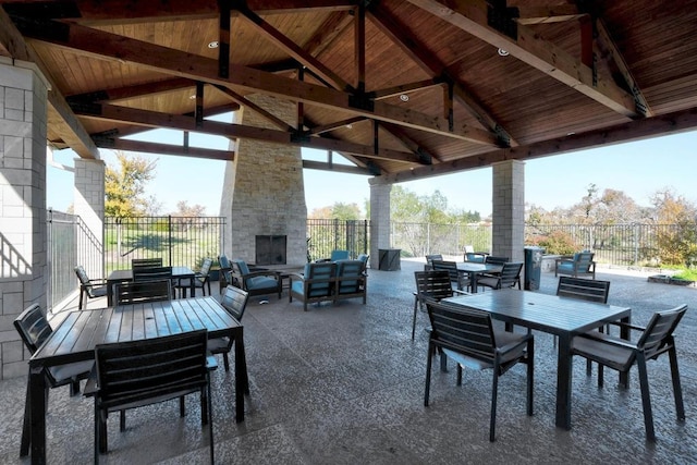 view of patio / terrace with a gazebo, outdoor dining space, an outdoor living space with a fireplace, and fence