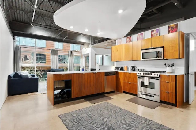 kitchen with stainless steel appliances, a peninsula, brown cabinetry, and light countertops