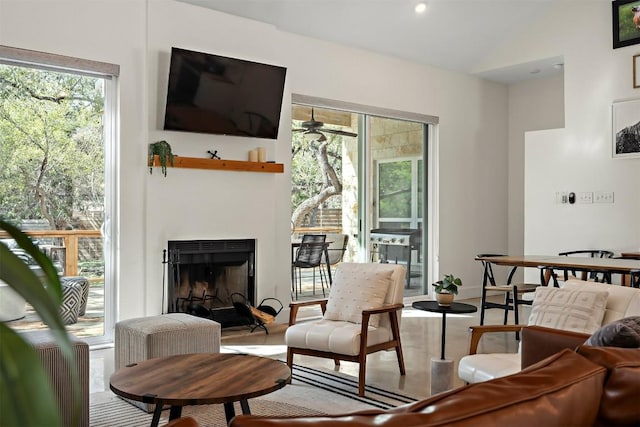 living room featuring lofted ceiling, a fireplace with raised hearth, and baseboards